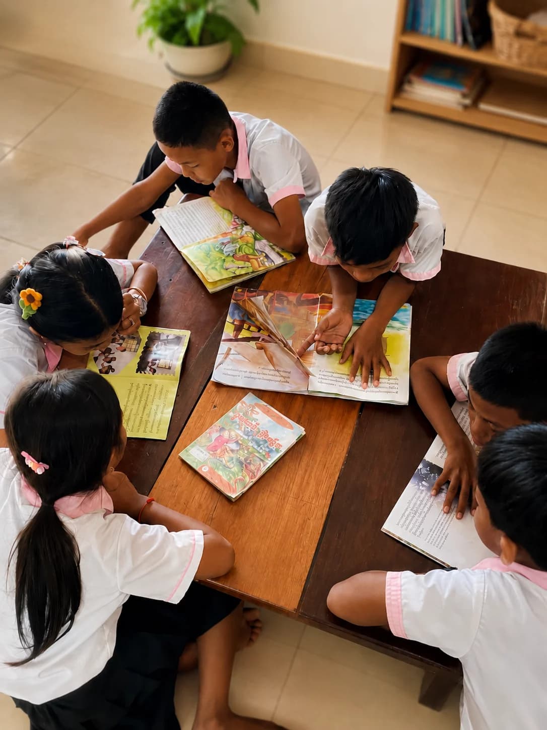 Children reading books together around a table
