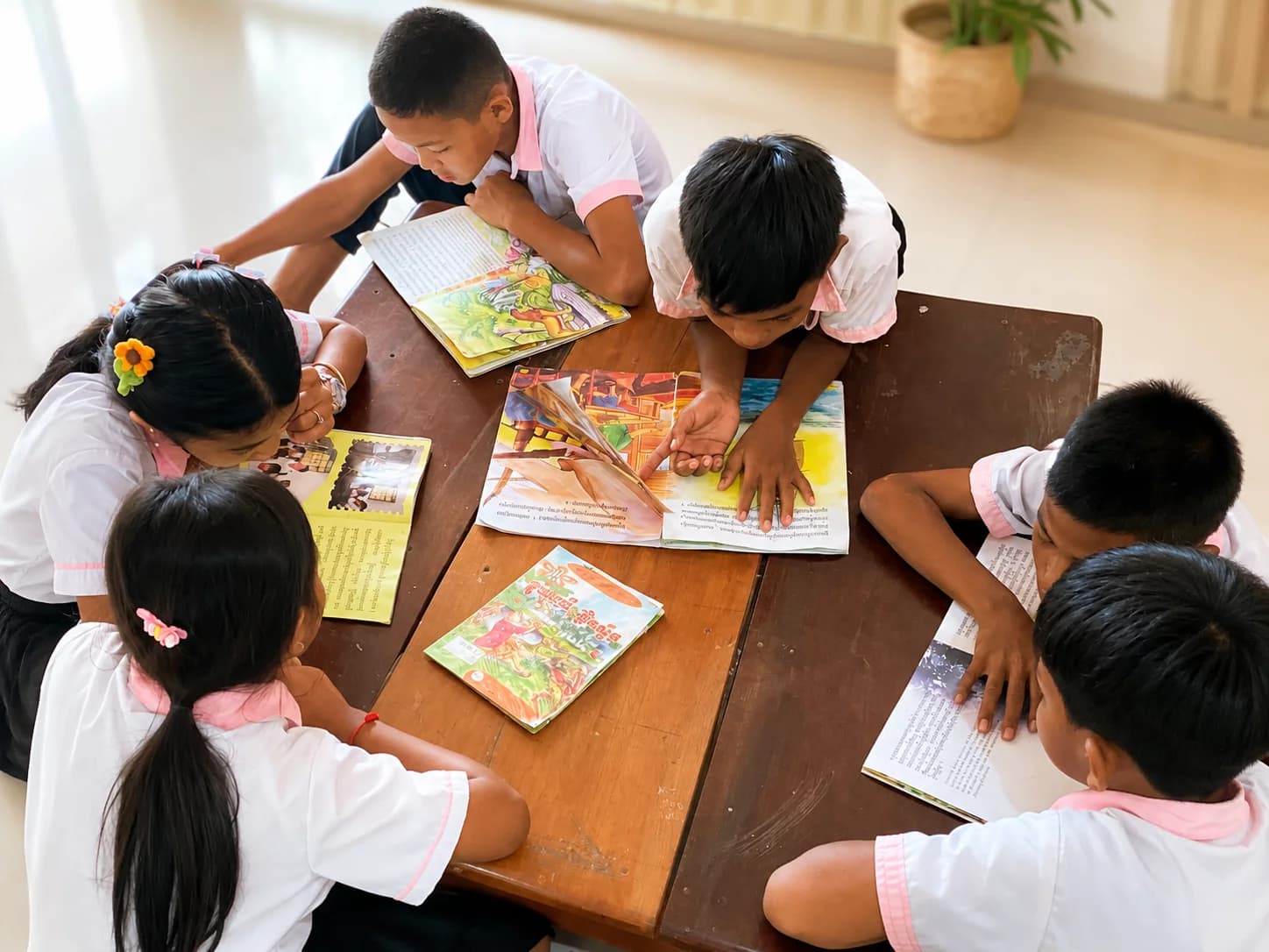 Children reading books together around a table