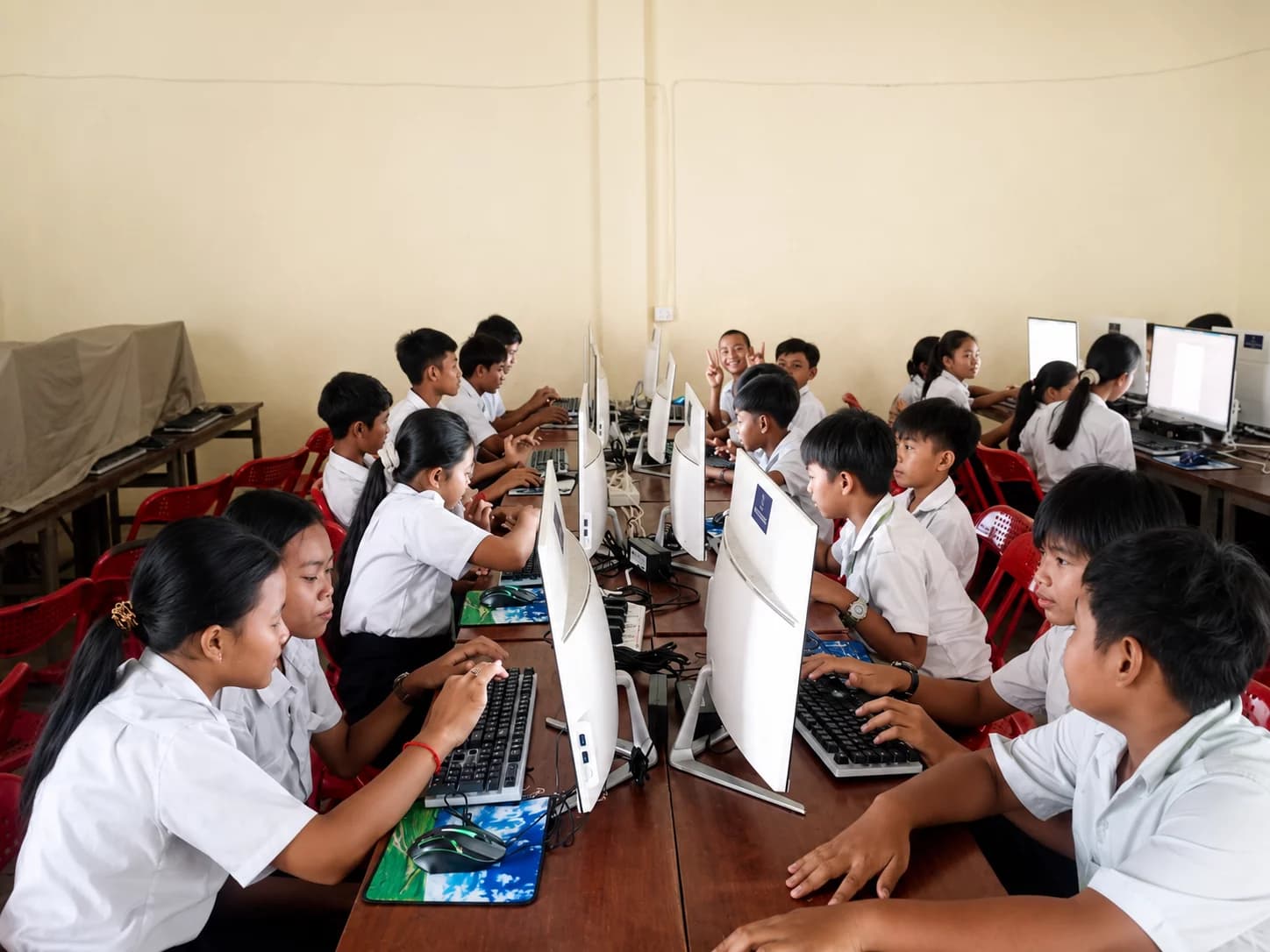 Students in school uniforms learning how to use desktop computers in a bright classroom computer lab